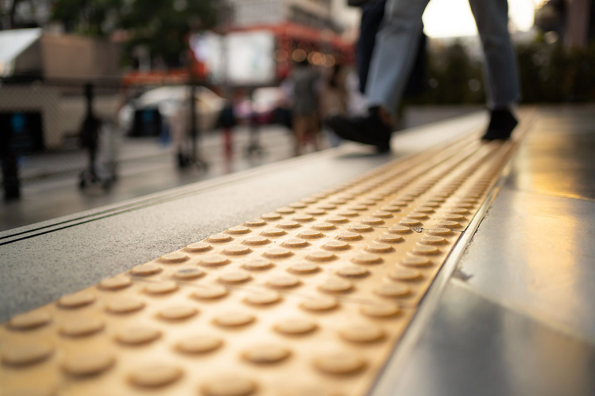 Pedestrian walking on tactile paving on footpath